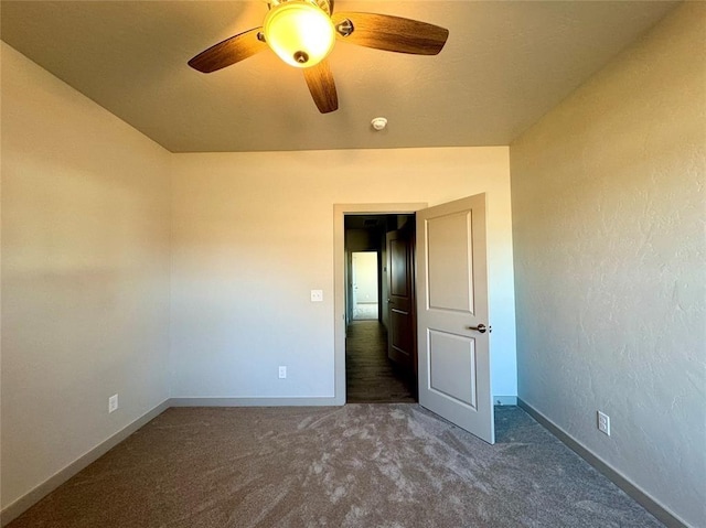 unfurnished room with ceiling fan and dark carpet