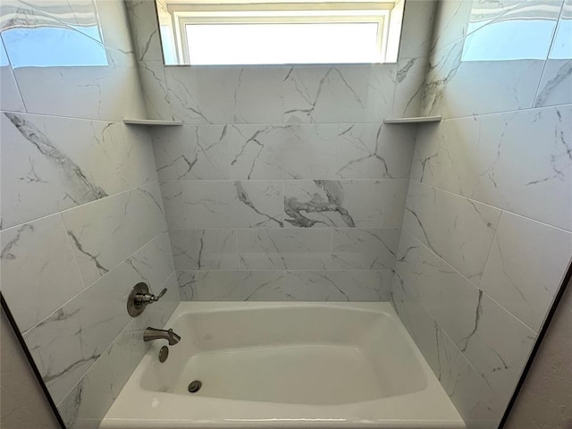 bathroom with a wealth of natural light and tiled shower / bath combo