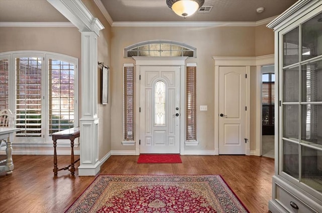 foyer entrance with dark hardwood / wood-style flooring, ornamental molding, and decorative columns