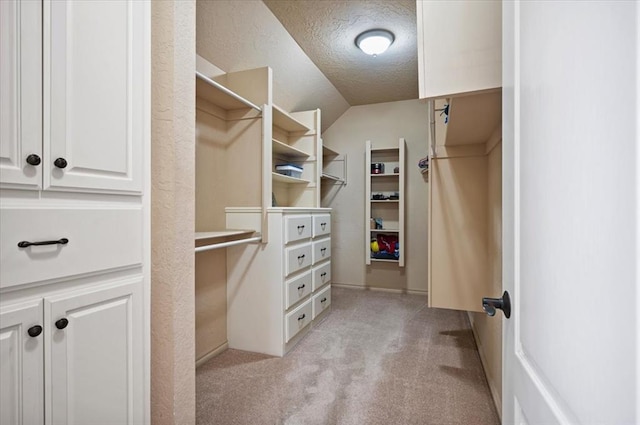 spacious closet featuring vaulted ceiling and light colored carpet