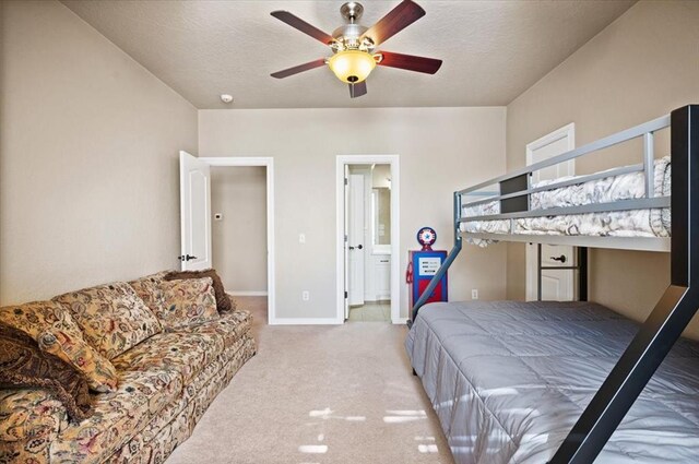 bedroom featuring ceiling fan, connected bathroom, light carpet, and a textured ceiling