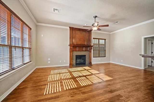 unfurnished living room with hardwood / wood-style flooring, crown molding, a fireplace, and ceiling fan