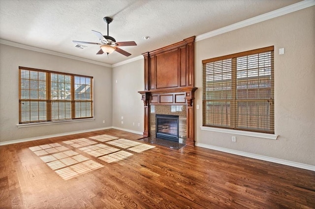 unfurnished living room with a textured ceiling, a fireplace, wood finished floors, visible vents, and ornamental molding