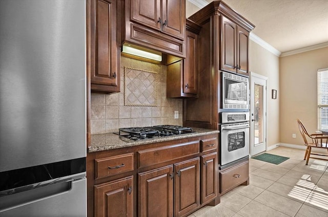 kitchen featuring crown molding, light tile patterned floors, stainless steel appliances, tasteful backsplash, and baseboards