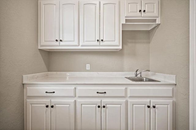 kitchen featuring white cabinetry, light countertops, and a sink