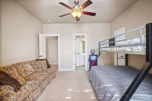 bedroom with baseboards, a textured ceiling, ensuite bathroom, and light colored carpet