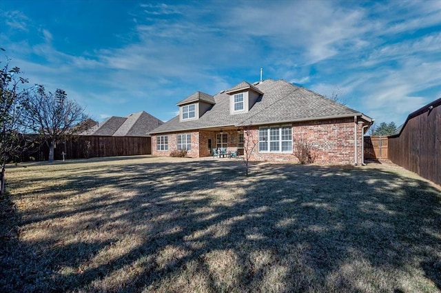 view of front of property with a fenced backyard, roof with shingles, a front lawn, and brick siding