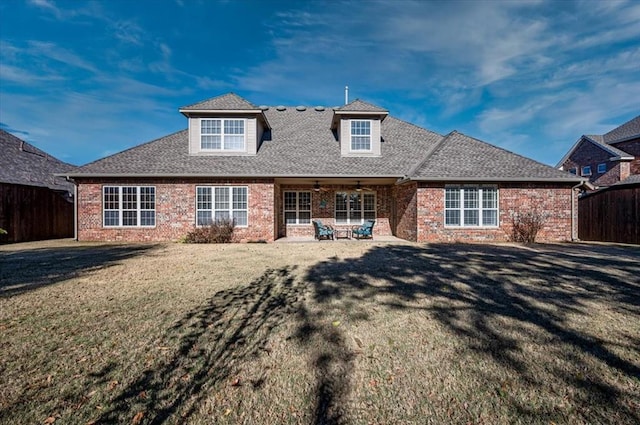 rear view of property featuring brick siding, fence, a ceiling fan, a lawn, and a patio area