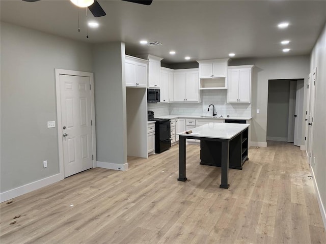 kitchen featuring white cabinets, a center island, sink, and black appliances