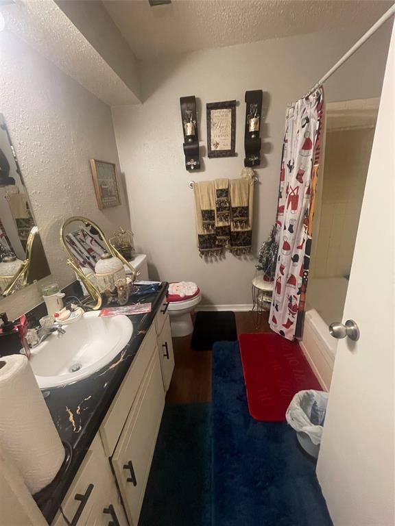 full bathroom with shower / bath combo, toilet, a textured ceiling, and vanity