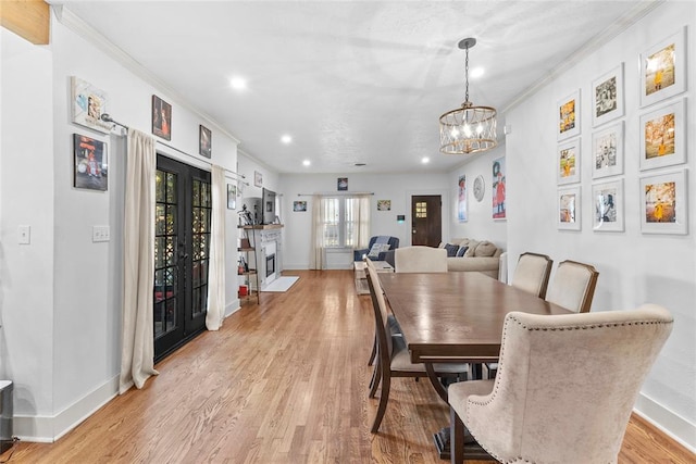 dining area featuring french doors, ornamental molding, a notable chandelier, and light hardwood / wood-style flooring