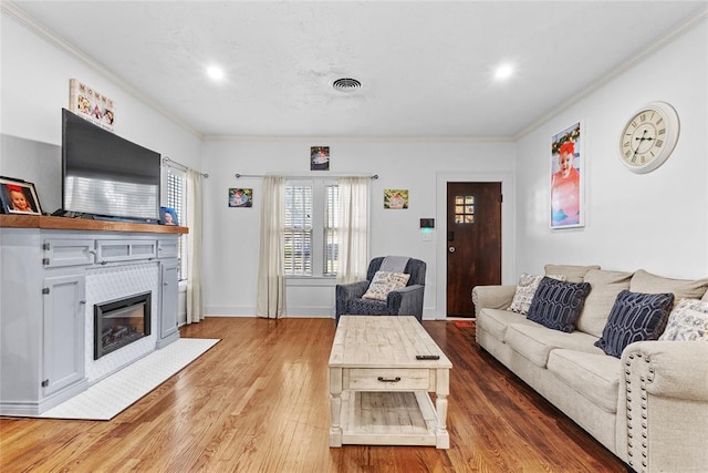 living room featuring a tile fireplace, hardwood / wood-style floors, and crown molding