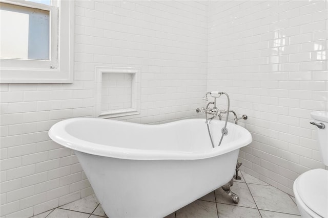 bathroom featuring tile patterned floors, a washtub, tile walls, and toilet