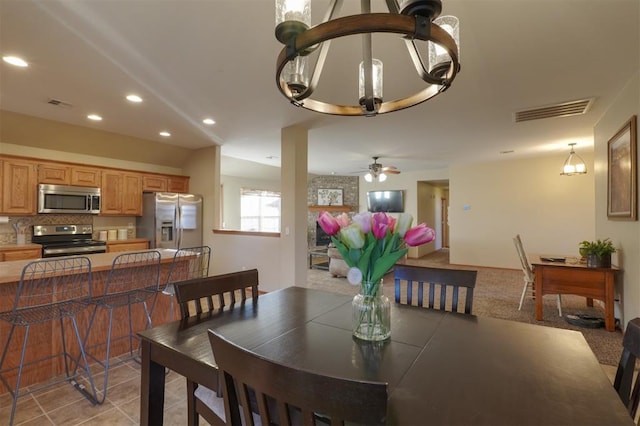 carpeted dining room with ceiling fan with notable chandelier