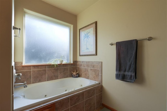 bathroom featuring a relaxing tiled tub and a healthy amount of sunlight