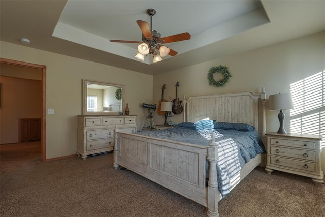 carpeted bedroom with a tray ceiling and ceiling fan