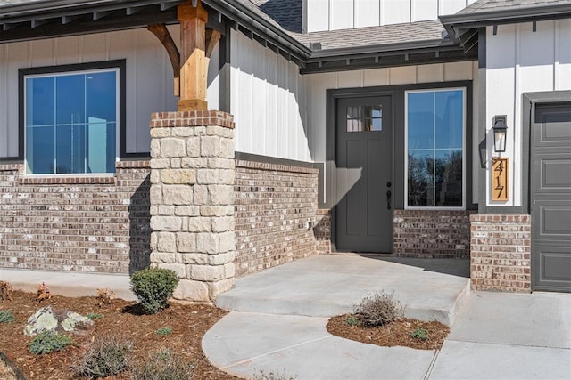 property entrance with board and batten siding, brick siding, and roof with shingles