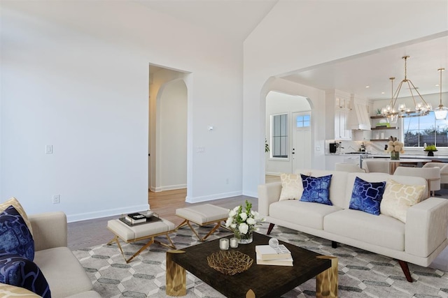 417 Basin Way, Norman, OK 73069 - living area featuring arched walkways, a chandelier, baseboards, light wood finished floors, and lofted ceiling
