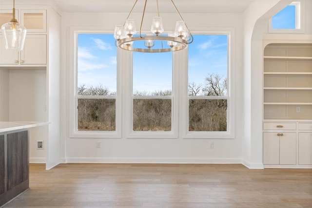 417 Basin Way, Norman, OK 73069 - unfurnished dining area with a chandelier, light wood-style flooring, and baseboards