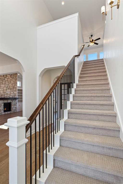 417 Basin Way, Norman, OK 73069 - staircase featuring a ceiling fan, a fireplace, arched walkways, wood finished floors, and baseboards
