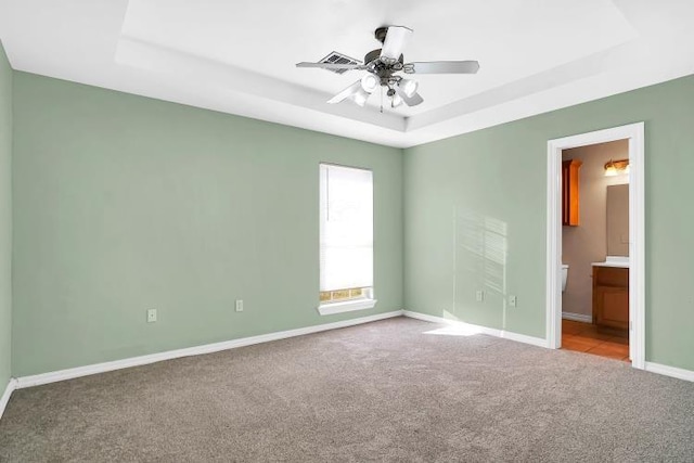 carpeted spare room with ceiling fan and a tray ceiling