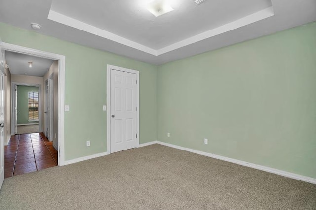 carpeted spare room featuring a raised ceiling