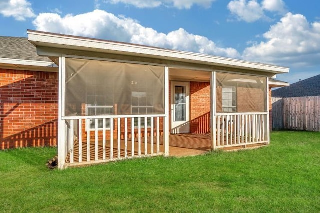 rear view of property with a lawn and a sunroom