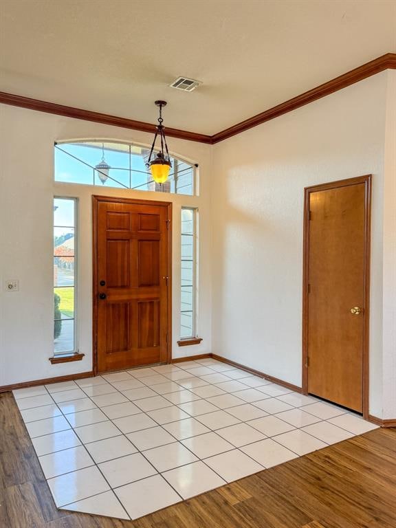 entrance foyer with light hardwood / wood-style floors, crown molding, and a wealth of natural light