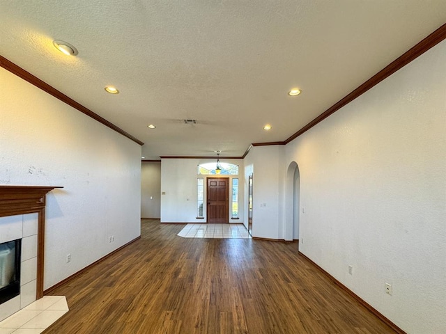 unfurnished living room featuring a fireplace, wood-type flooring, a textured ceiling, and ornamental molding