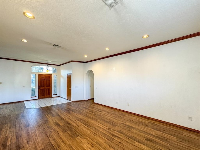 unfurnished room featuring a textured ceiling, light hardwood / wood-style floors, and crown molding