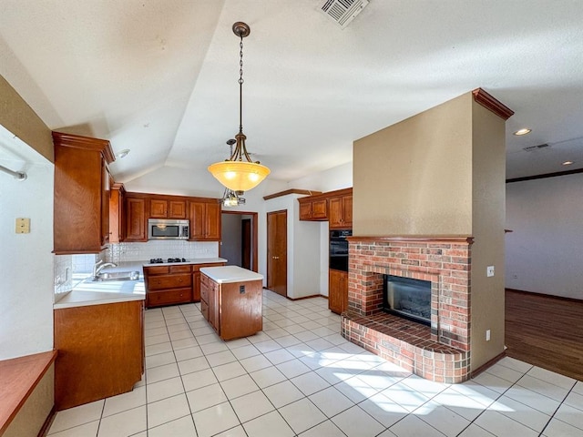 kitchen featuring sink, stainless steel appliances, a kitchen island, decorative light fixtures, and light tile patterned flooring