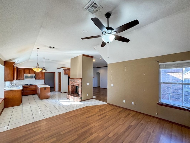 kitchen with pendant lighting, a center island, lofted ceiling, and light hardwood / wood-style flooring