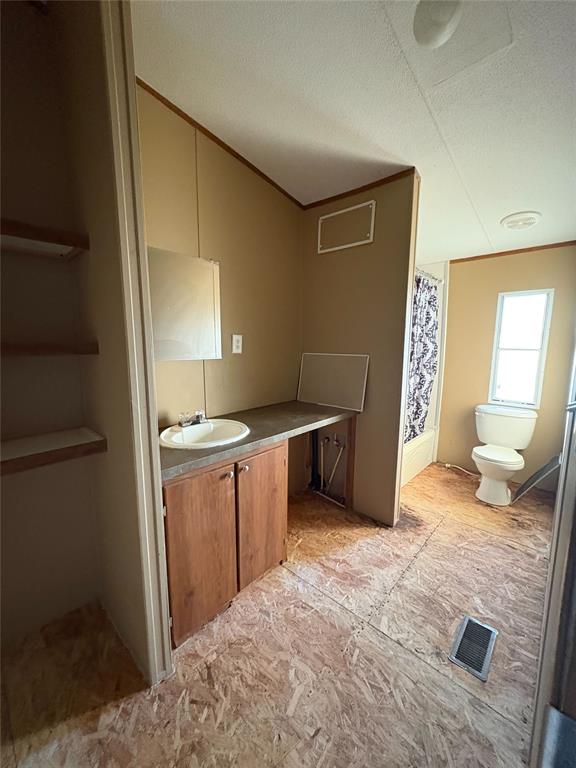 bathroom with a shower with shower curtain, vanity, toilet, and a textured ceiling