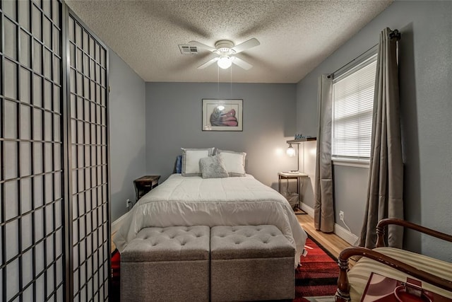 bedroom featuring ceiling fan, wood-type flooring, and a textured ceiling