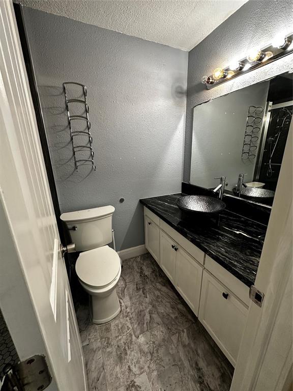 bathroom with a textured ceiling, toilet, and vanity