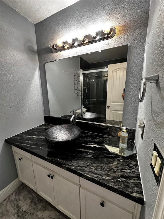 bathroom featuring a textured ceiling, a shower with door, and vanity