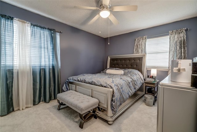 bedroom with light carpet, ceiling fan, and a textured ceiling