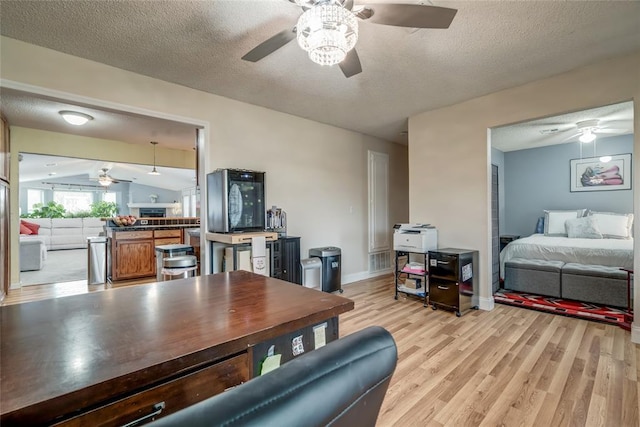 interior space with a textured ceiling, lofted ceiling, kitchen peninsula, and light wood-type flooring