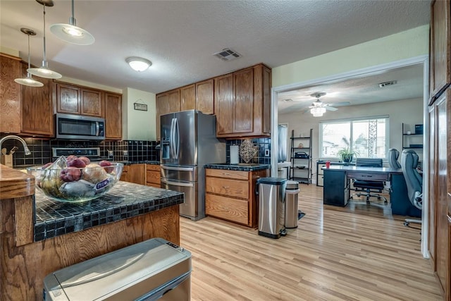 kitchen featuring a textured ceiling, pendant lighting, stainless steel appliances, and tasteful backsplash