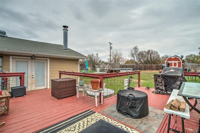 wooden terrace with a shed, a yard, and area for grilling