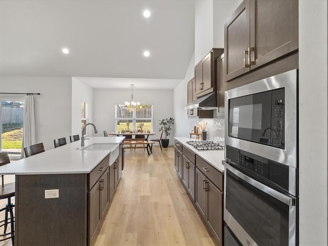 kitchen with a kitchen breakfast bar, a wealth of natural light, an island with sink, and appliances with stainless steel finishes