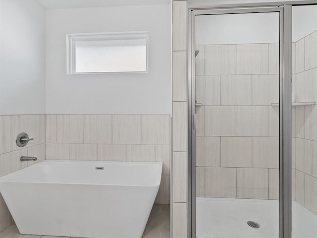 bathroom featuring tile walls and independent shower and bath