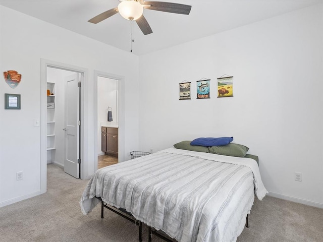 carpeted bedroom featuring ensuite bath, ceiling fan, and a walk in closet