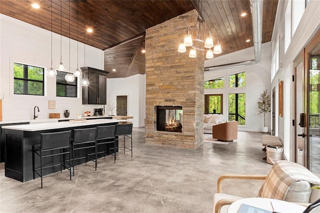 kitchen with a wealth of natural light, a breakfast bar, high vaulted ceiling, and wooden ceiling