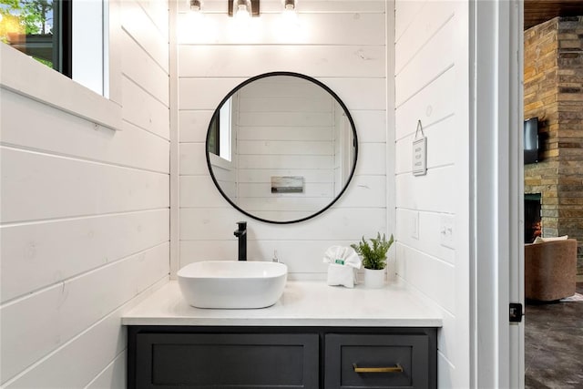 bathroom featuring a fireplace, vanity, and wood walls