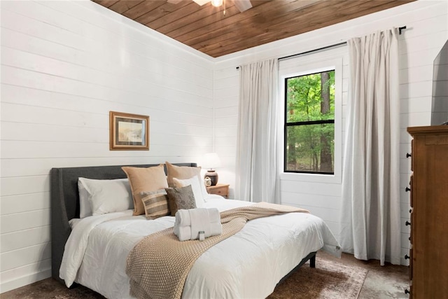 bedroom featuring ceiling fan, wooden walls, and wood ceiling