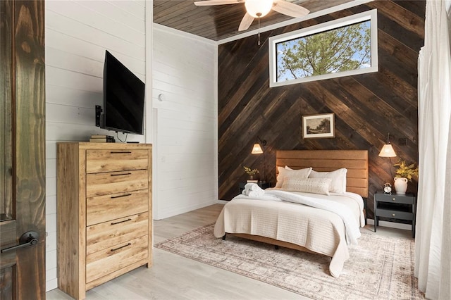 bedroom with hardwood / wood-style floors, ceiling fan, and wooden walls