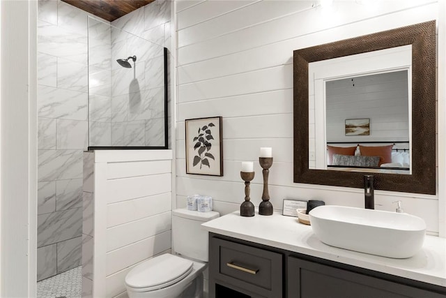 bathroom featuring a tile shower, vanity, toilet, and wood walls