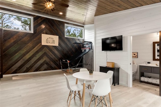 dining area with wood walls, light wood-type flooring, wood ceiling, and vaulted ceiling