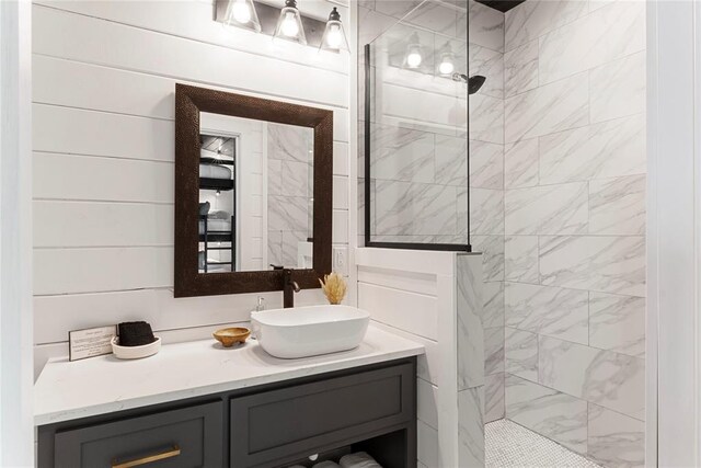 bathroom with a tile shower and vanity